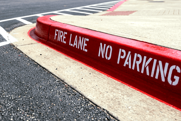 Red fire lane curb painting with NO PARKING stenciling on commercial property