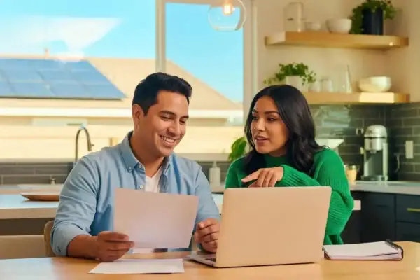 A family sitting together at a dining table reviewing government incentives and finding the best way to finance solar panels for their home.