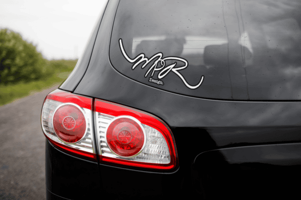 Black car with "MPR Design" sticker on the rear window.