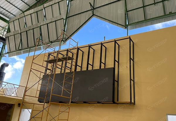 Outdoor LED display installation in progress with scaffolding and metal frame structure on a hotel wall in Barbados