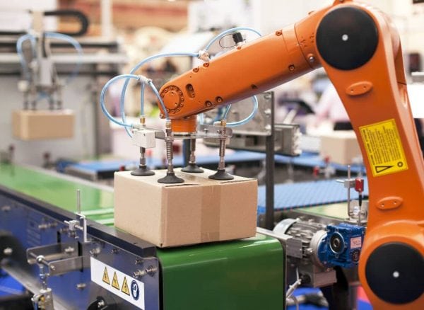 Brazo robótico automatizado manipulando una caja en una línea de producción.