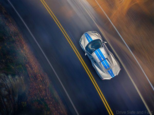Overhead view of 2024 Chevrolet Corvette E-Ray 3LZ convertible in Silver Flare with Electric Blue stripe package driving on a road. Pre-production model shown. Actual production model may vary. Model year 2024 Corvette E-Ray available 2023.