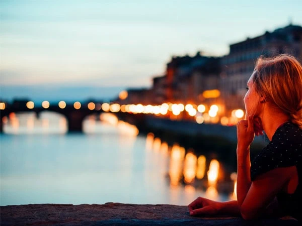 A student looks out over the Arno river in Florence, Italy