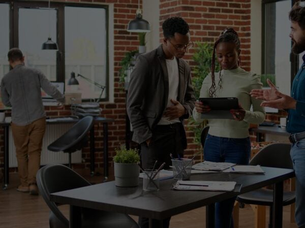 Two people standing at a table with papers and laptops.