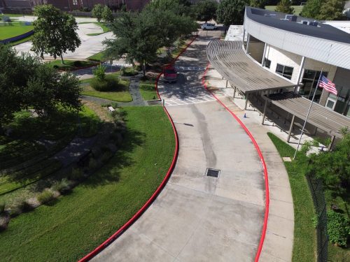 Aerial view of a red fire lane curb painted along the circle drive at a Montessori school in Houston, TX