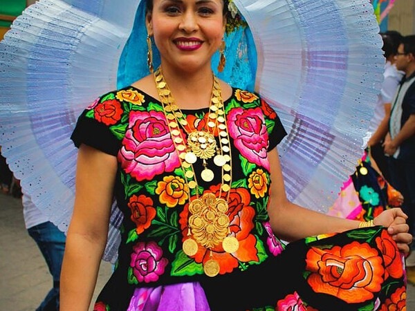pexels-photo-12314629-12314629 A woman proudly showcases a vibrant traditional floral dress at a Mexican festival.