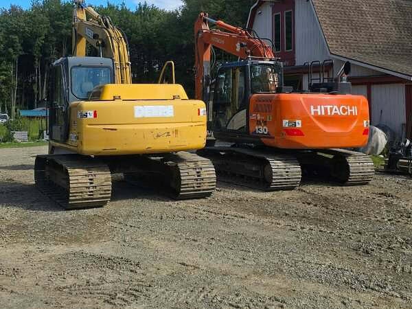 Excavation in Jamestown, NY Yellow John Deere excavator and orange Hitachi 130 excavator parked side by side in the yard beside a barn