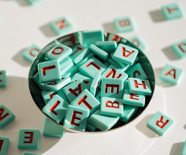 A collection of colorful letter tiles spilling from a metal bowl, arranged creatively.