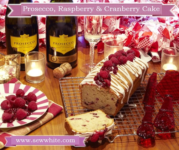 Prosecco Raspberry and Cranberry Cake drizzled with icing and topped with fruit and served with a glass of prosecco