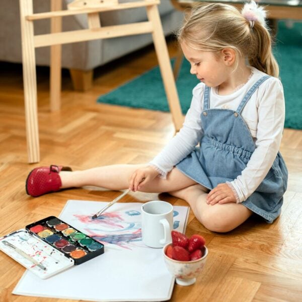 Leon Kinder Lederclogs 4800 Rot – kleines Mädchen malt mit Wasserfarben auf dem Boden