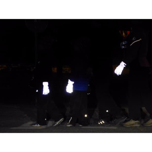 Heijastavat toppahanskat koko perheelle. Pimeässä aikuinen ja kaksi lasta ja kaikilla heijastavat toppahanskat kädessä.