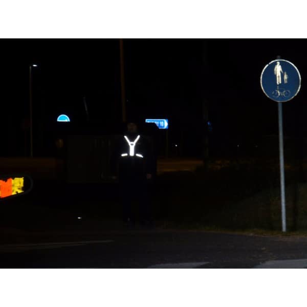 Jalankulkija suojatiellä. Hänellä on päällään Huomio Heijastava Sporttiliivi joka loistaa pimeässä.