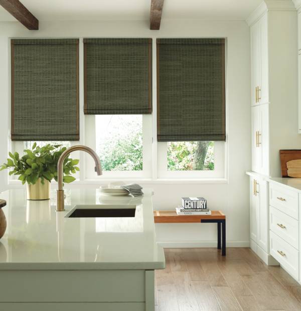 Bright kitchen with stylish gray window shades and natural light. Modern white cabinetry and greenery create inviting space.