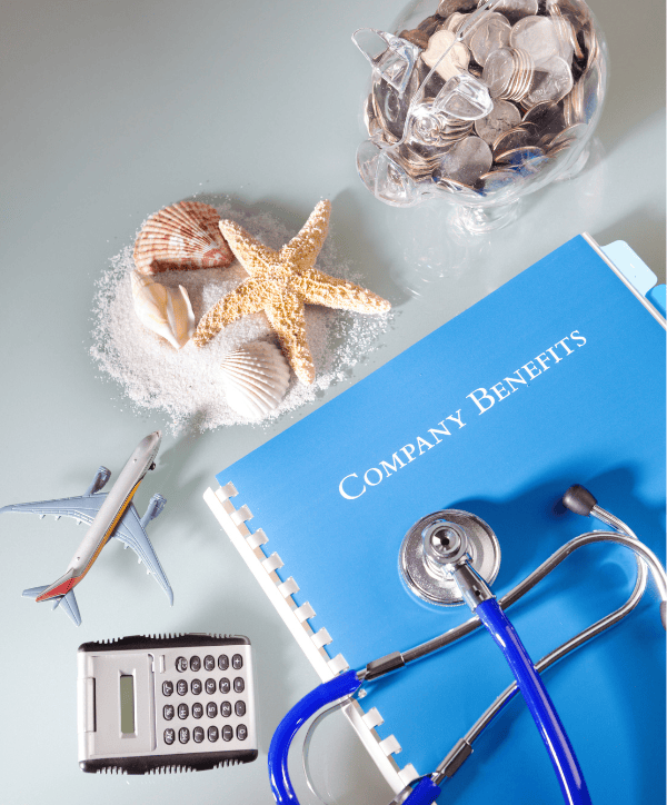 Block mit der Aufschrift „Company Benefits“, daneben Sparschweine, Muscheln, ein Seestern und ein Hörgerät – symbolisiert finanzielle, gesundheitliche und urlaubsbezogene Mitarbeiter-Benefits