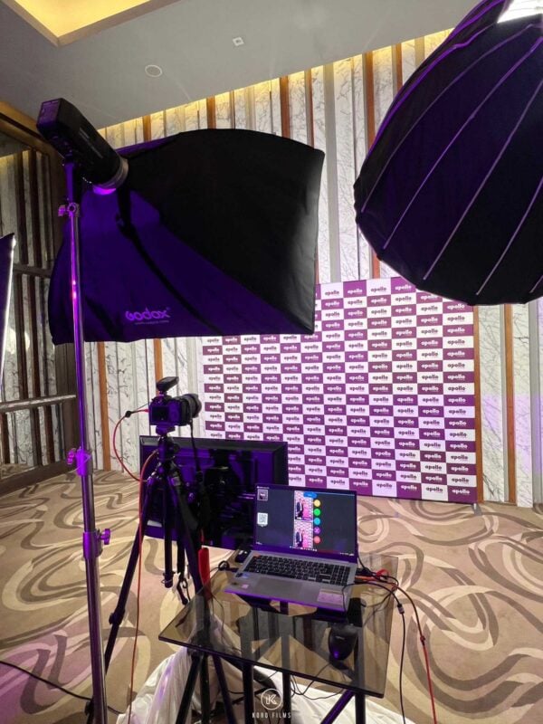 Magnet photo booth camera, softbox lighting and laptop set up in front of a logo backdrop