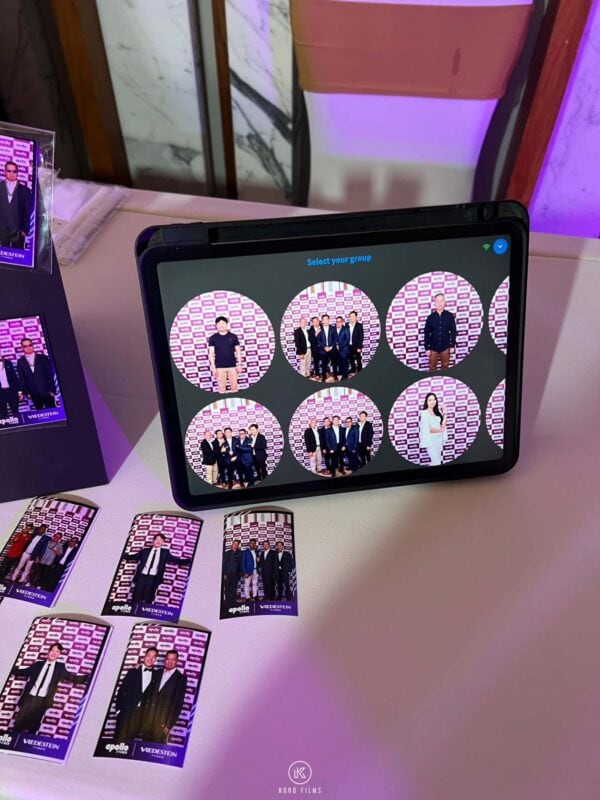 Tablet showing guests' photos next to finished photo magnets in clear sleeves