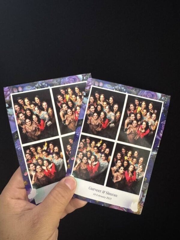 Hand holding two top view photo booth prints with a floral wedding frame