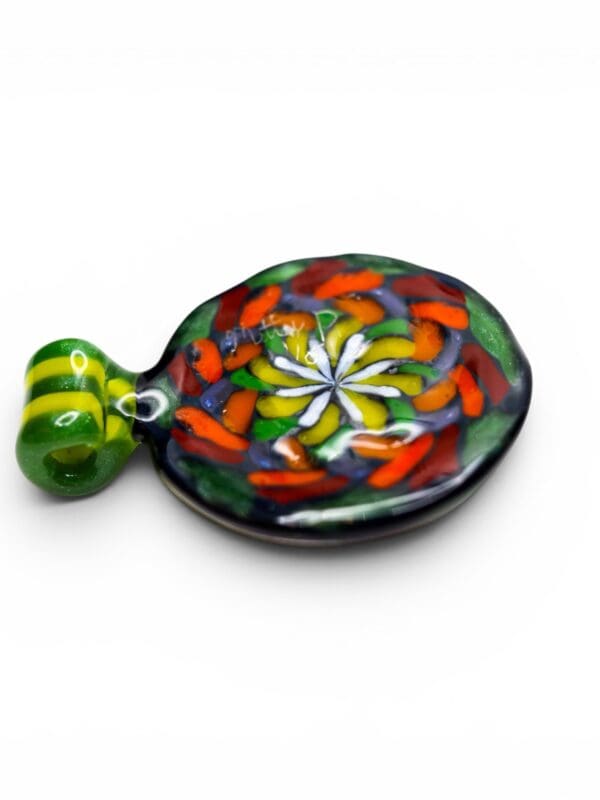 Side angle view of the Filla Rainbow Mandala Glass Pendant with colourful handcrafted glass mandala pattern and striped green loop.