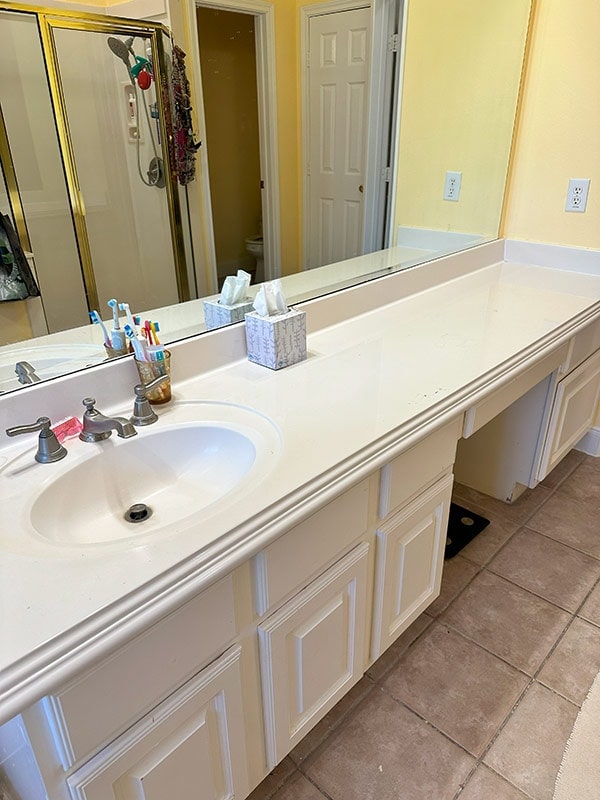 Clean bathroom vanity with large mirror and organized toiletries, bright yellow walls, and a spacious countertop, perfect for relaxation and self-care routines.