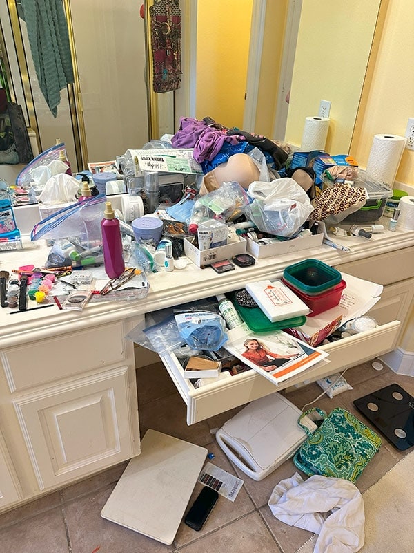 Cluttered bathroom vanity with makeup, toiletries, and personal care products, messy space, disorganized personal items, chaotic beauty station, bathroom organization problem, unfocused beauty space, cluttered dresser for cleaning or decluttering concept.