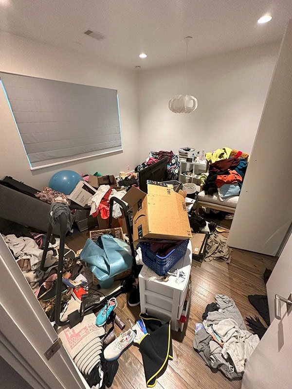 Cluttered bedroom overflowing with clothes and miscellaneous items, messy space, disorganized room, chaotic living area, disarray, disorder, living space cleaning, home organization, cluttered room photo.