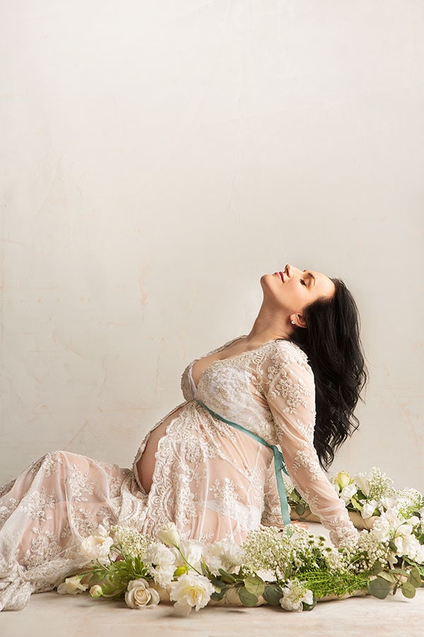 Kvinnelig gravid kvinne i rolig posisjon med blomster, gravidfoto, mager gravid mage, blomsterdekorasjon, gravidfoto, vakkert svangerskapsbilde, gravidfotografering, morskap, kvinne med svangerskapsplagg, graviditet dokumentasjon, elegant gravidbilde, gravidfoto inspirasjon.