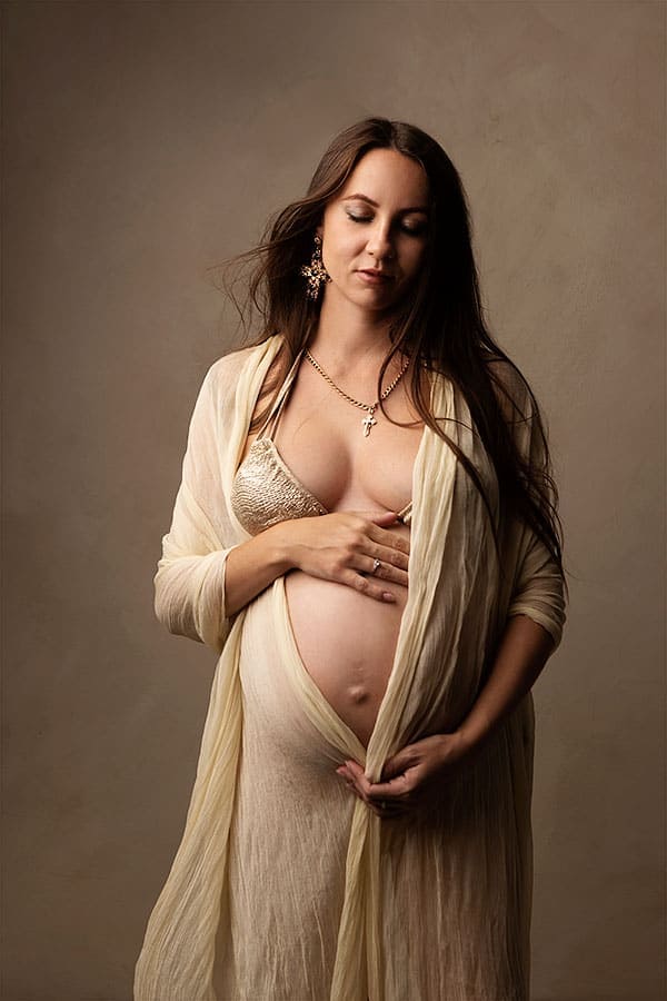 Gravidfoto gravidfotografering med gravid kvinne i elegant kjole, fremhever den vakre mageregionen, instilsjon av ro og glede i svangerskapet i et profesjonelt studio.