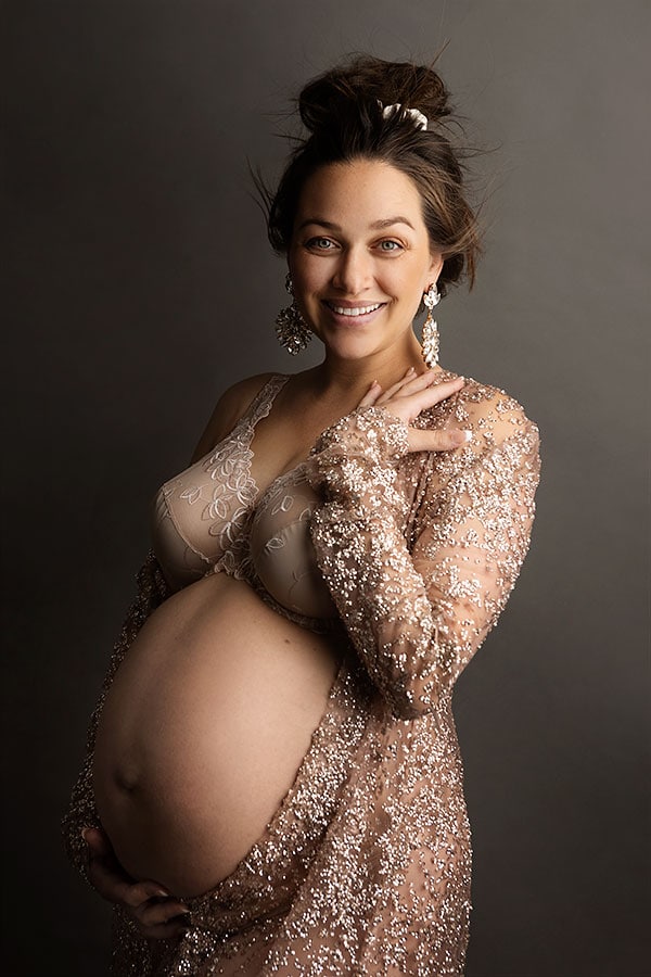 Elegant gravidfoto av smilende gravid kvinne i glamorøst antrekk for gravidfotografering. Perfekt for gravidefoto, maternity fotografering, og spesialfanger for mødre.