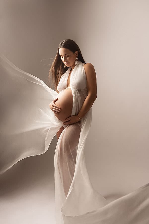 Nydelig gravidfotografibilde av en kvinne i elegant klær som viser hennes voksende mage, perfekt for mødre som ønsker unike og stemningsfulle gravidfotografier.