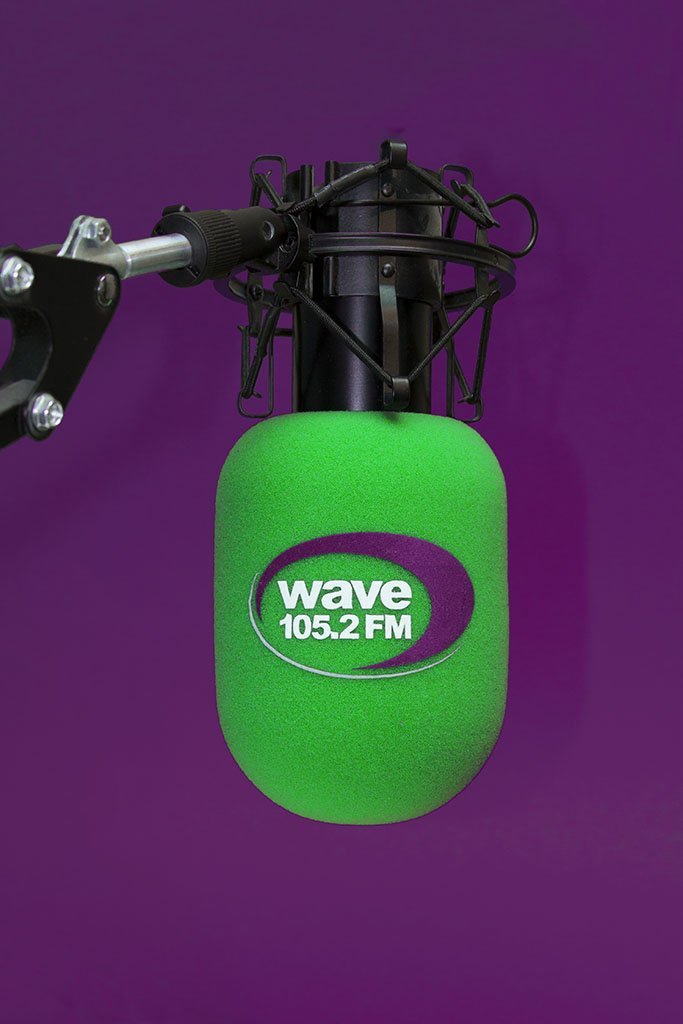 Wave 105.2 FM branded studio microphone windshield with bright green cylindrical foam cover and purple logo