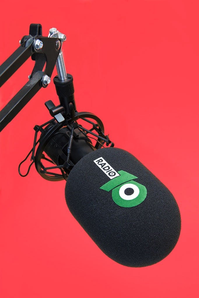Branded studio microphone windshield with black cylindrical foam cover and green logo on boom arm