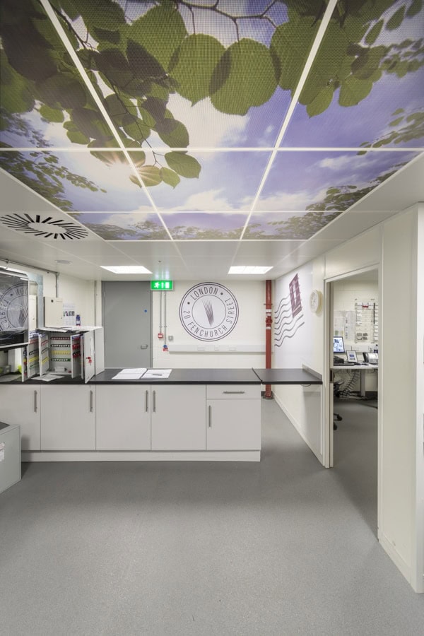 Image showing the internal view of a post room. The ceiling design features a photograph of a view of a blue sky seen through tree leaves. The back and left hand walls are decorated with large postage stamp graphics.