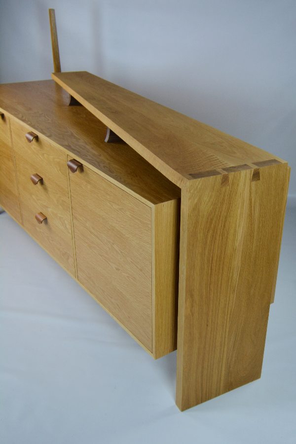 Made for a customer who wanted something different as when she was shopping around found most of the cabinets, she was looking at were just large rectangles. The design started as just a concept drawing which she like and we when from there. The use of the black walnut in the bent laminated handles and supports was chosen to match the flooring in her house. As part of the brief, she wanted something that didn’t look like something she had bought from a shop. The mitered thought dovetail was to give the piece a handmade feature and with the shape of the legs to the tapers and angles in the shelf for the subtle and elegant design which make this feature piece stand out but keeps usability and storage.