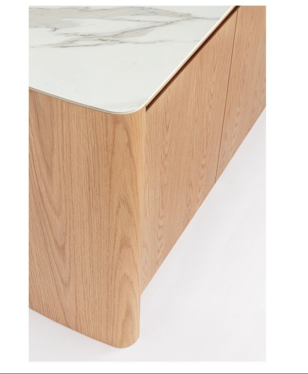 Close-up of a light wood cabinet with a white marble top and curved bottom edge.