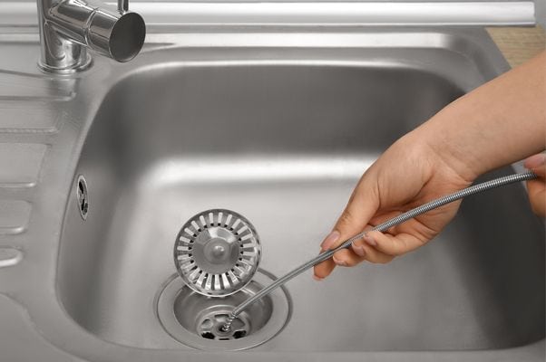 Technician using drain snake in kitchen sink