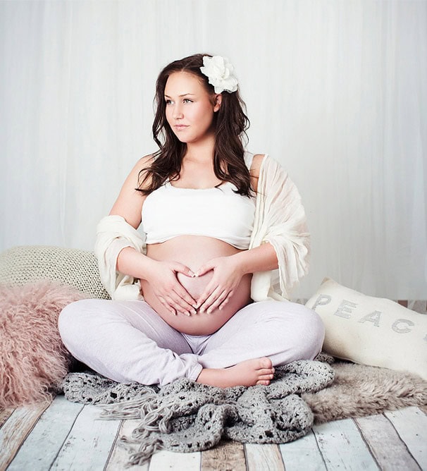 Elegant gravidfoto av en forventningsfull kvinne som viser sin gravide mage i et lyst og koselig hjem, perfekt for å forevige graviditeten.