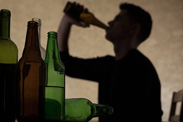 Person holding alcohol bottle – effects of drinking, ETG test detection, and alcohol consumption awareness.