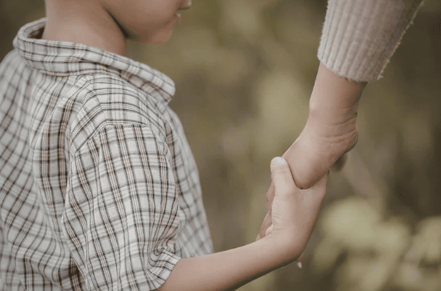 Close-up of a child holding an adult’s hand, symbolizing trust and reliability in trip applications for family travel planning.