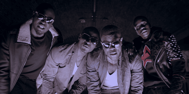 Cinematic music video production shot featuring a performance scene with a group of men on an urban London indoor football pitch.