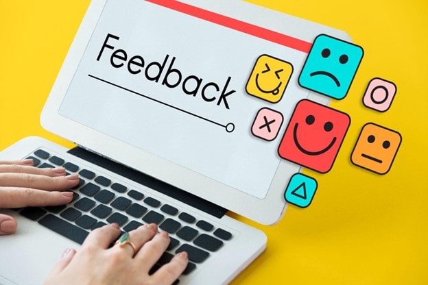 Digital feedback form on a laptop screen with colorful emoji faces and symbols.