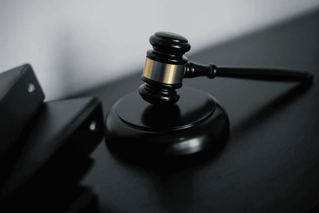 Close-up of a wooden judge's gavel resting on its base against a dark background.