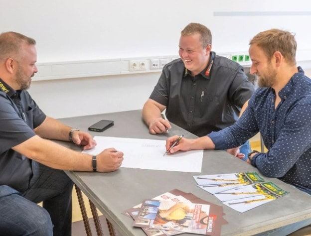 Ein Team von Winkler sitzt beim Tisch und arbeitet an einem Kundenprojekt. Es wir ein Plan gezeichnet