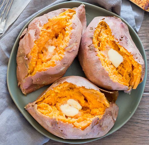 overhead shot of microwaved sweet potatoes with butter on a green earthenware plate