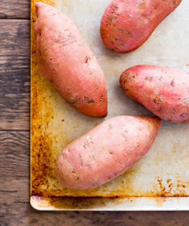 raw sweet potatoes on a sheet pan