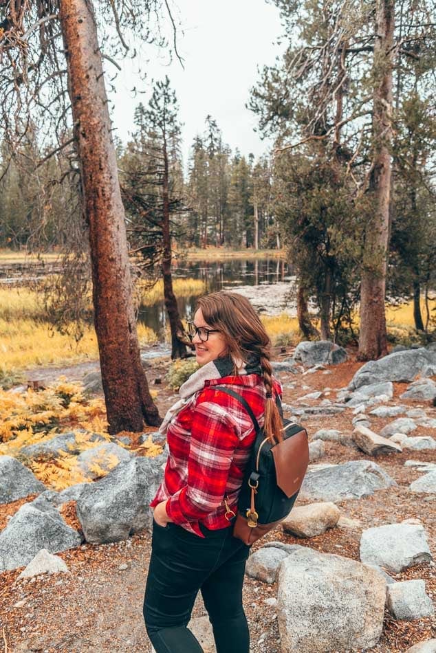 Exploring Yosemite National Park in the fall in a red flannel shirt, scarf, and backpack.