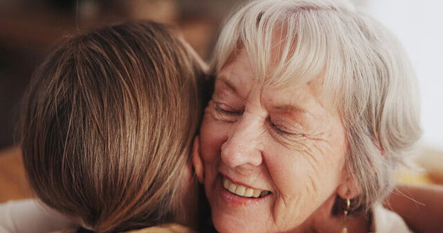 Woman, love and hug senior mom in home for mothers day, bonding and visit in retirement with care or happy. Person, smile and embrace with elderly parent for reunion, comfort and affection in hospice