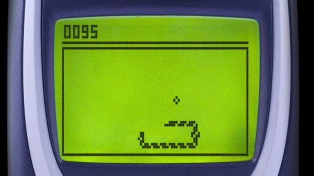 Close-up of a classic mobile phone screen displaying the Snake game, with the pixelated snake moving toward a dot to eat it and the score “0095” shown at the top left corner.