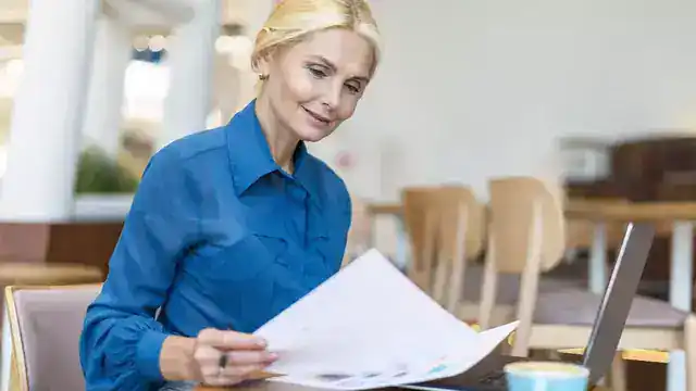 Femme consultant des documents administratifs, illustration du calcul du plafond PER