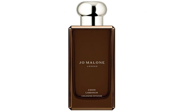JO MALONE Amber Labdanum Cologne Intense bottle surrounded by wild citrus, amber labdanum, vanilla pods, and roasted oak