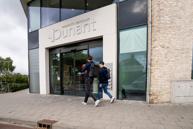 Twee fysiotherapeuten lopen de praktijk van Fysiotherapie Dunant in Roosendaal binnen.